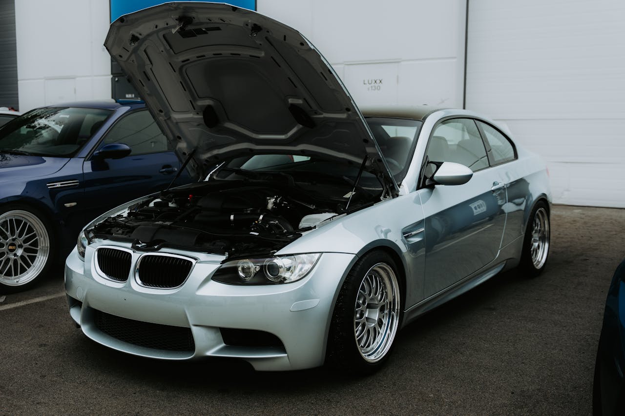 services-09 Silver car with open hood in a parking lot. Automotive maintenance scene.